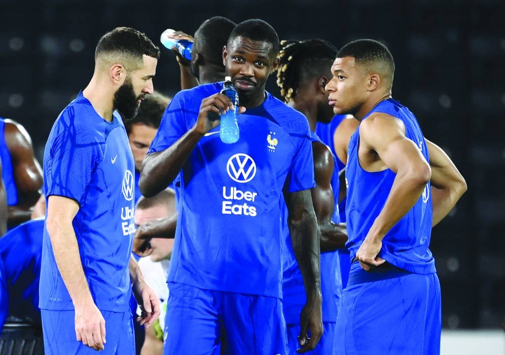 France’s Karim Benzema (left) speaks with Kylian Mbappe (right) and Marcus Thuram during a training session at the Jassim Bin Hamad Stadium in Doha yesterday. (AFP)