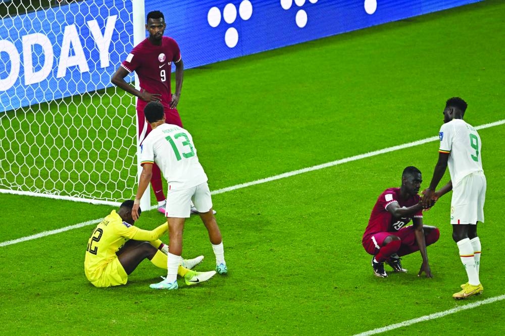 Qatar players are consoled by Senegal players after the match at Al Thumama Stadium. (AFP)