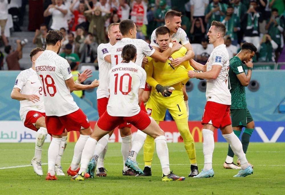 Poland's Wojciech Szczesny celebrates with teammates after saving a penalty kick.