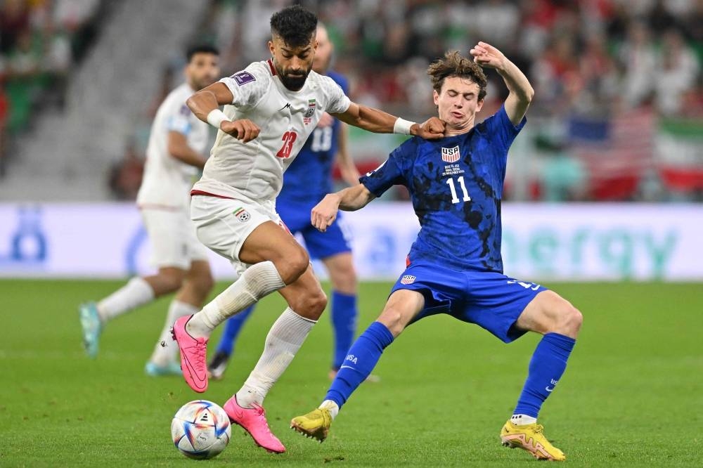 Iran's defender Ramin Rezaeian fights for the ball with USA's midfielder Brenden Aaronson during the Group B match at the Al-Thumama Stadium in Doha
