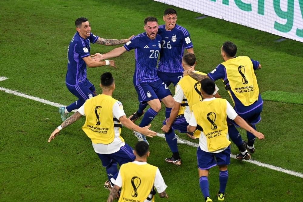 Argentina's midfielder Alexis Mac Allister (C) celebrates with teammates after scoring his team's first goal against Poland.