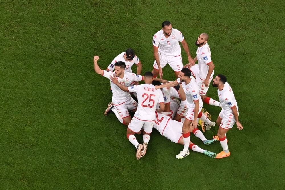 Tunisia's forward #10 Wahbi Khazri (hidden) celebrates scoring the opening goal with his teammates during the Qatar 2022 World Cup Group D football match between Tunisia and France at the Education City Stadium.