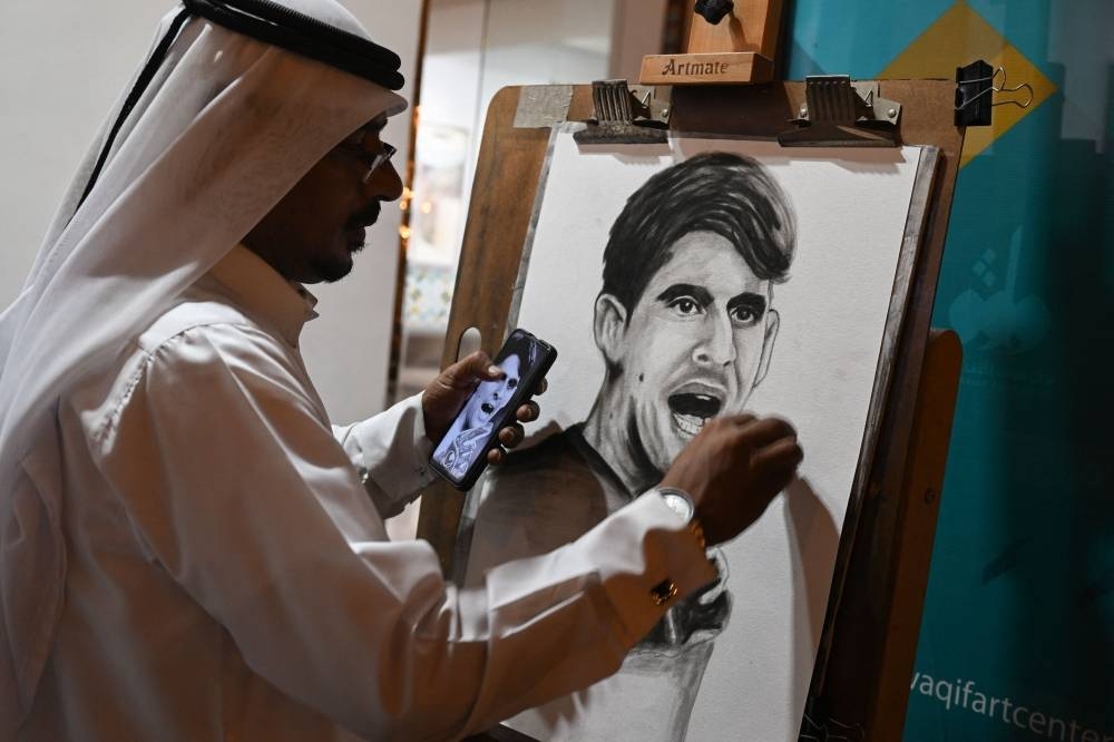 An artist paints a portrait of Morocco's goalkeeper Yassine Bounou in Doha Tuesday after their team won the Qatar 2022 World Cup round of 16 football match between Morocco and Spain.