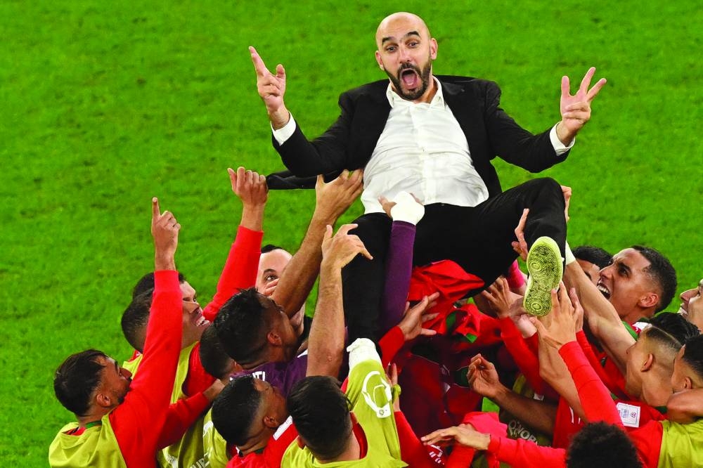 Morocco players throw coach Walid Regragui in the air as they celebrate their win over Spain at the Education City Stadium in Al Rayyan yesterday. (AFP)