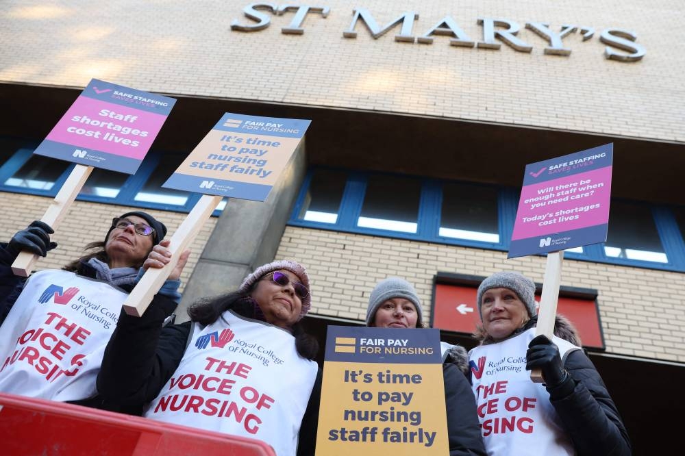 Healthcare workers hold placards at a picket line outside St Mary's Hospital in west London (AFP)