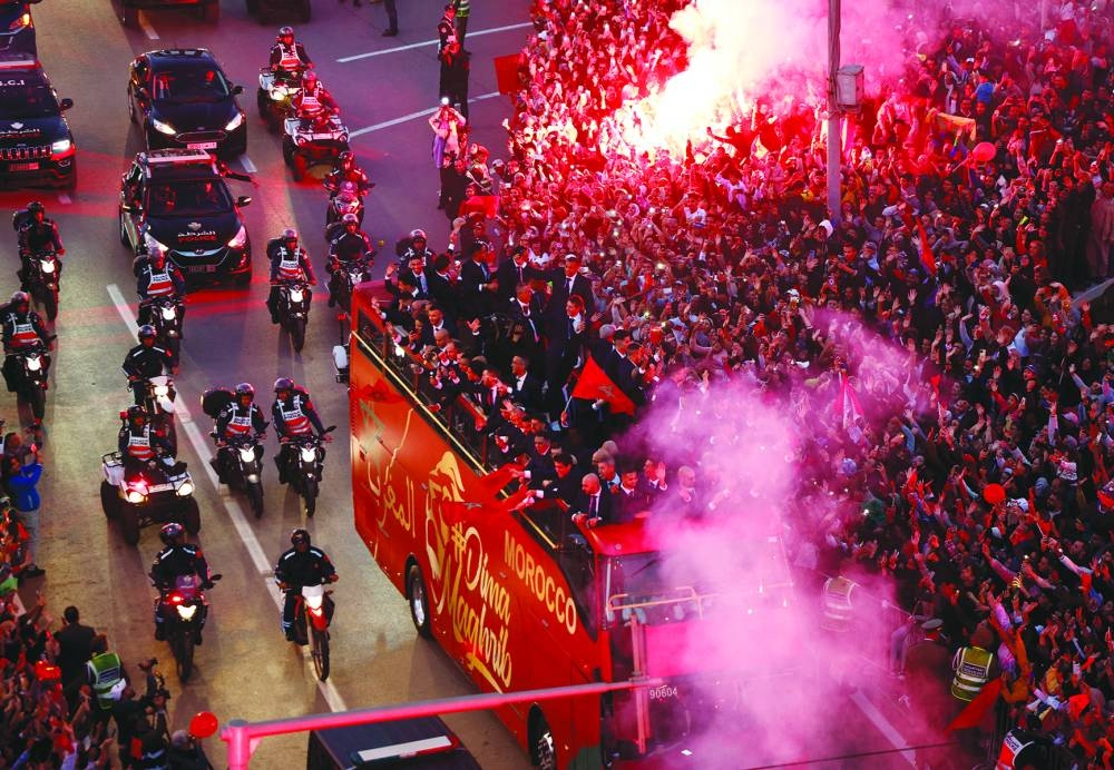 Soccer Football - FIFA World Cup Qatar 2022 - Morocco return after the World Cup - Rabat, Morocco - December 20, 2022
Morocco players wave flags on a bus as police officers stand guard and fans celebrate with flares REUTERS/Juan Medina