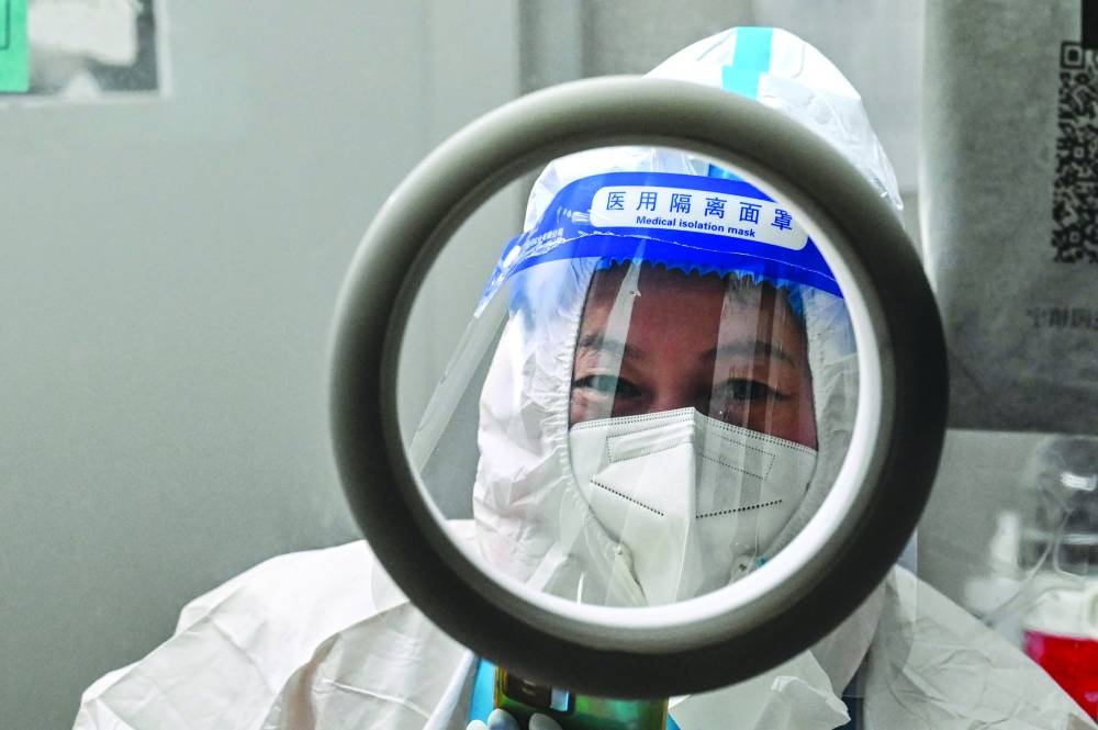A health worker waits for people to take swab samples to test for the Covid-19 in the Jing’an district in Shanghai. 