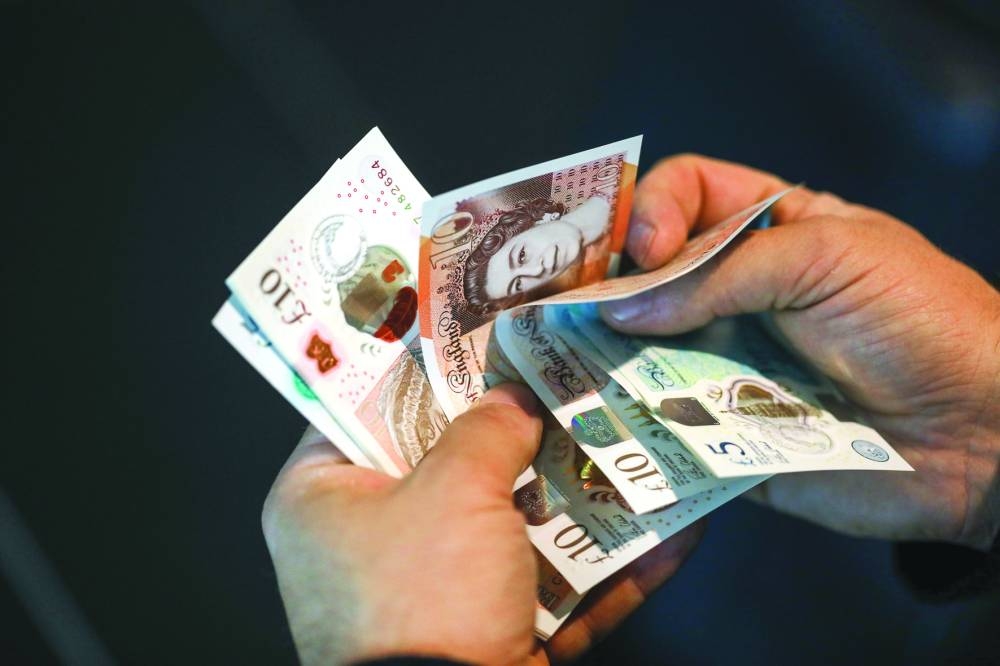 A man holds pound sterling banknotes in an arranged photograph in London. A turbulent year for the pound is coming to an end with little evidence that 2023 will be much different.