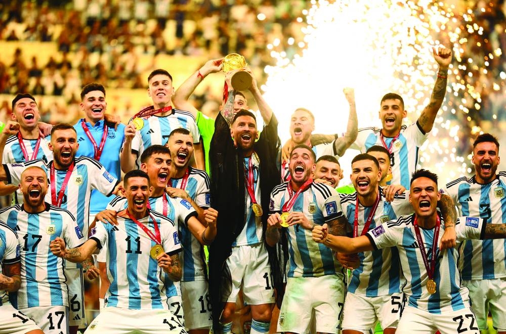Argentine captain Lionel Messi lifts the World Cup trophy alongside his teammates as they celebrate after beating France 4-2 in a penalty shootout at the end of a pulsating final at the Lusail Stadium on December 18. (Reuters)
