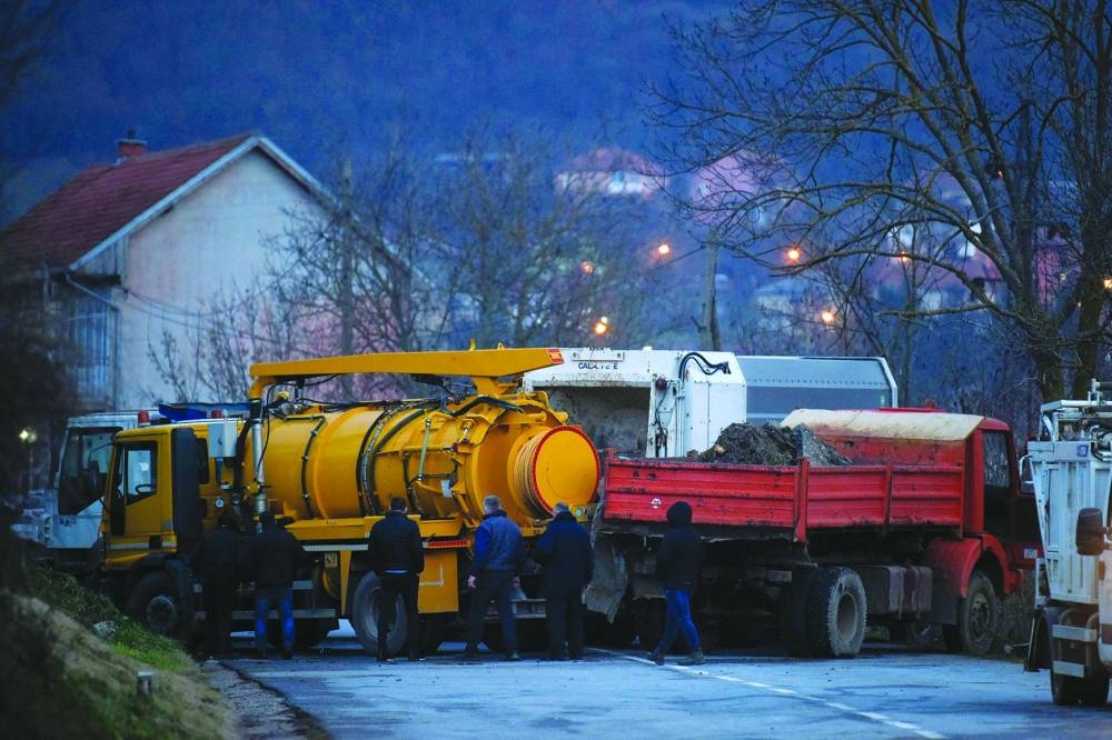 Bystanders remove trucks from a road barricade set up by ethnic Serbs in the village of Rudare near the town of Zvecan yesterday. (AFP)