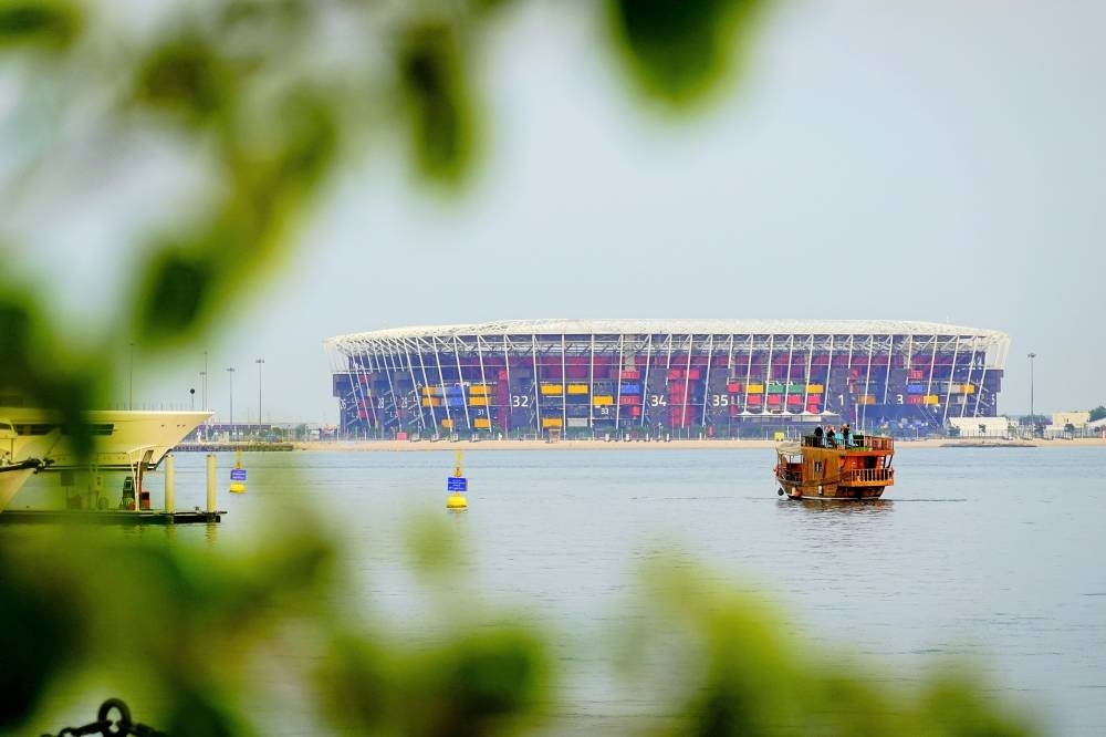 A group of tourists on a dhow get a close view of Stadium 974, as seen from the Old Doha Port.