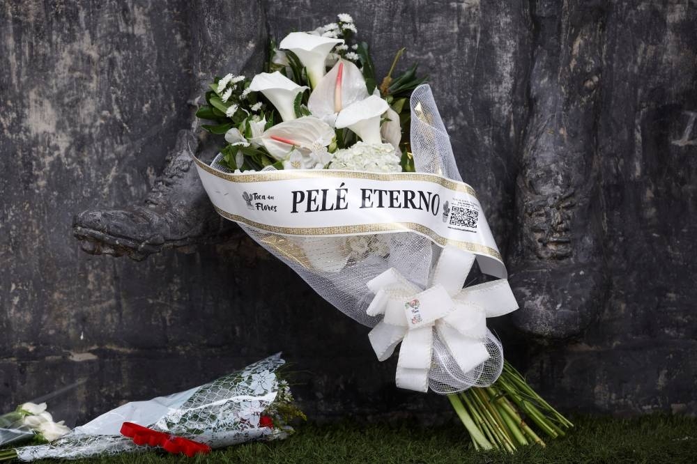 A bouquet of flowers reading "Eternal Pele” is seen in front of a statue of Brazilian soccer legend Pele at the Vila Belmiro stadium as his fans mourn his death, in Santos, Brazil. REUTERS
