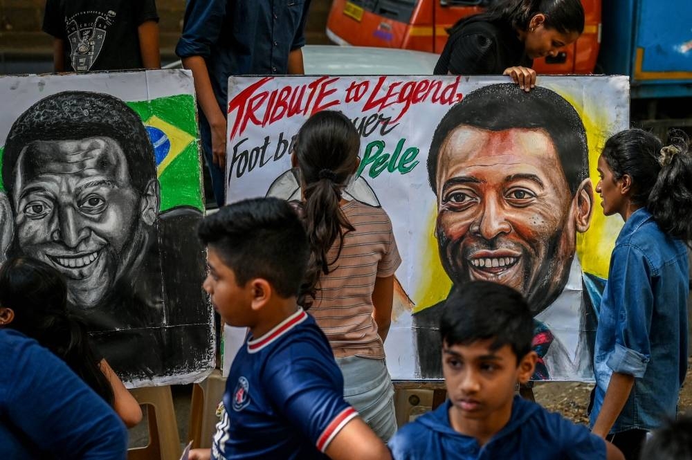Students stand around paintings of Brazilian football legend Pele as a part of tribute, at a art school in Mumbai on December 30, 2022.