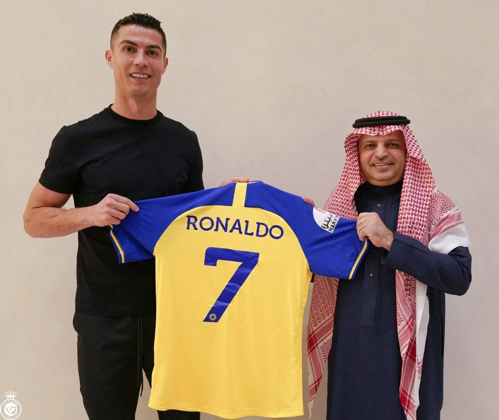 A handout picture released by Saudi Arabia's Al Nassr football club on their Twitter account shows Portugal's forward Cristiano Ronaldo being presented with the club's number seven jersey by club president Musalli Al-Muammar in Madrid (AFP)