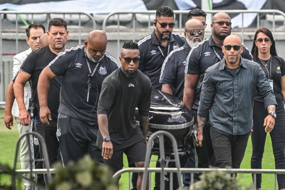 People headed by the son of late Brazilian football legend Pele, Edinho, transport his coffin into the Urbano Caldeira stadium in Santos, Sao Paulo, Brazil. AFP