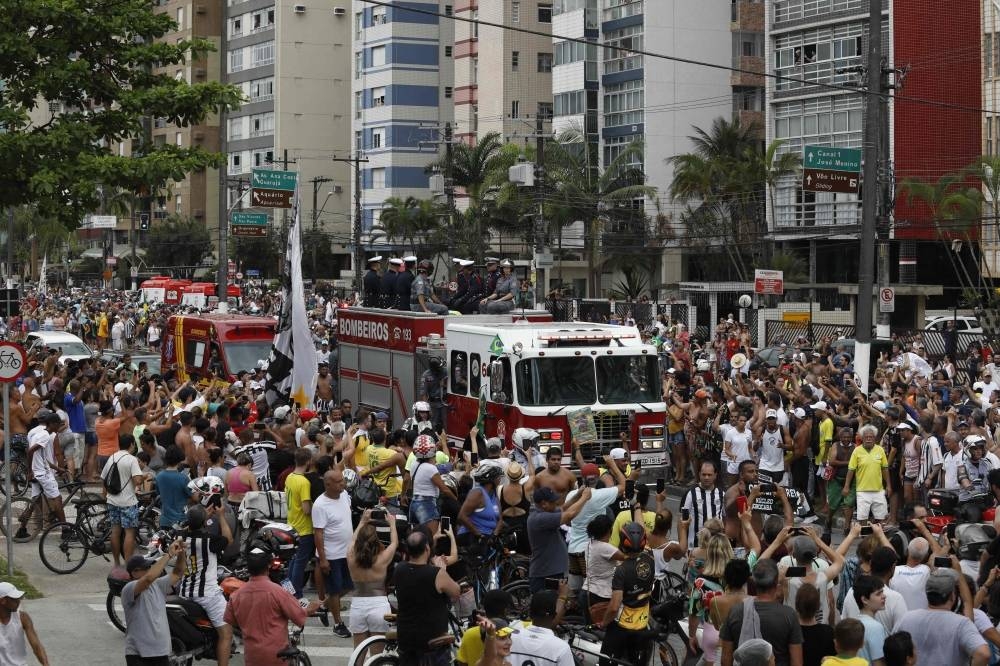Fans of the late Brazilian football star Pele gather on the street as a firetruck transports Pele's coffin to the Santos' Memorial Cemetery in Santos, Sao Paulo state, Brazil on January 3. AFP