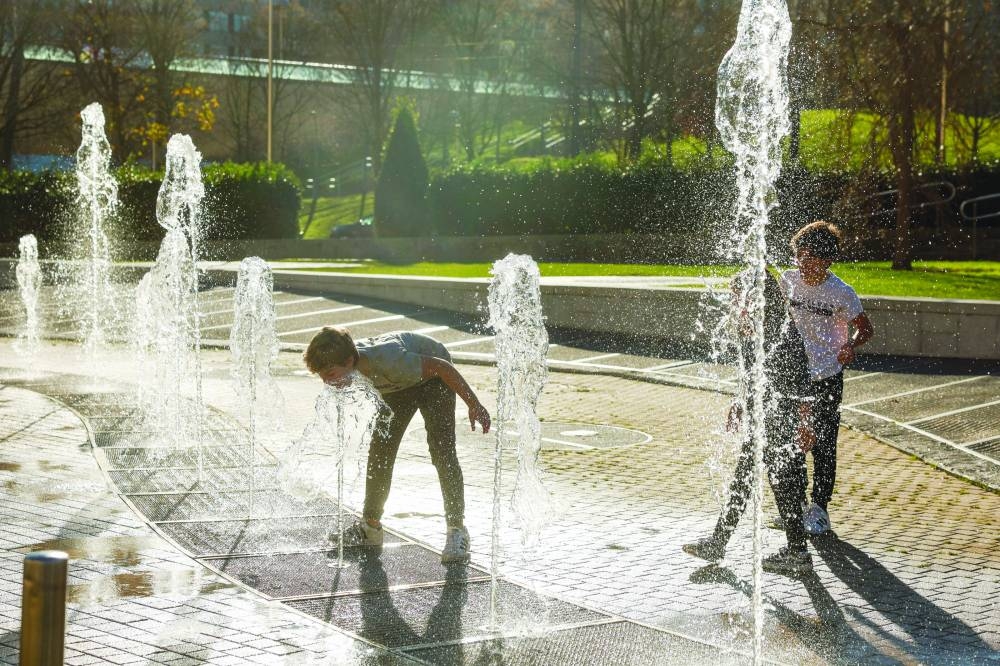 Boys play in a fountain during unseasonably warm temperatures in Bilbao, Spain, yesterday. (Reuters)