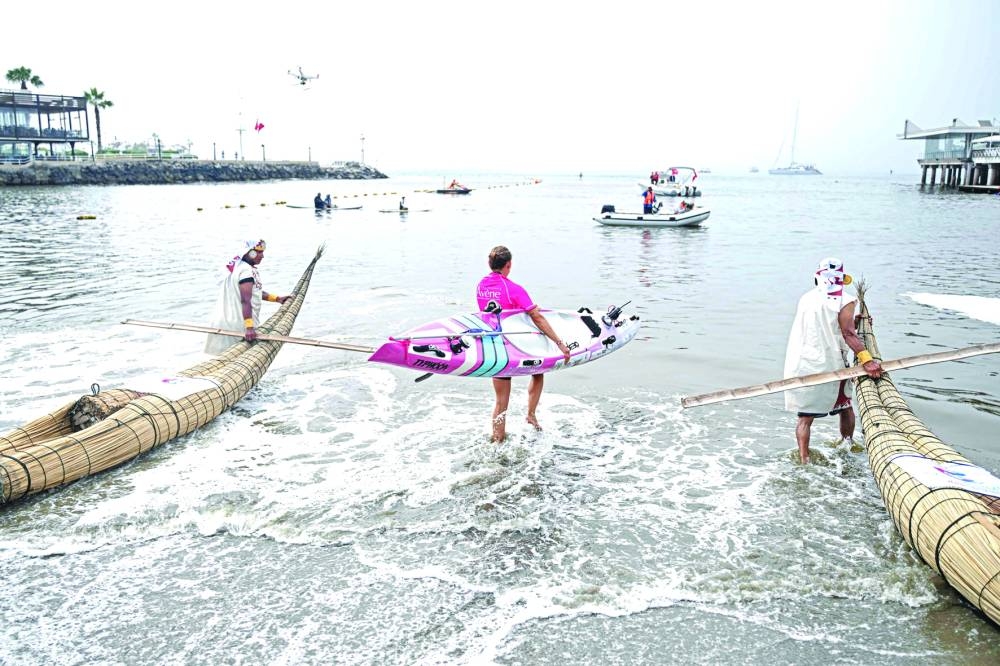 Itziar Abascal gets into the ocean next to two men dressed as people from the Moche civilisation paddling their ‘Caballitos de Totora’, a type of boat used to navigate since ancient times, as she departs from the Regatas Lima Club in Lima.