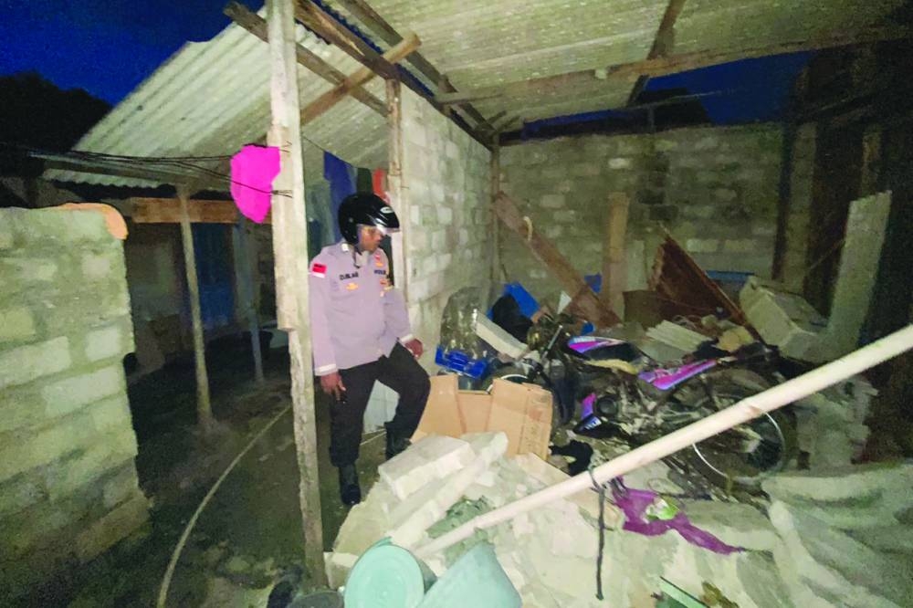 A police officer checks a damaged house. 
