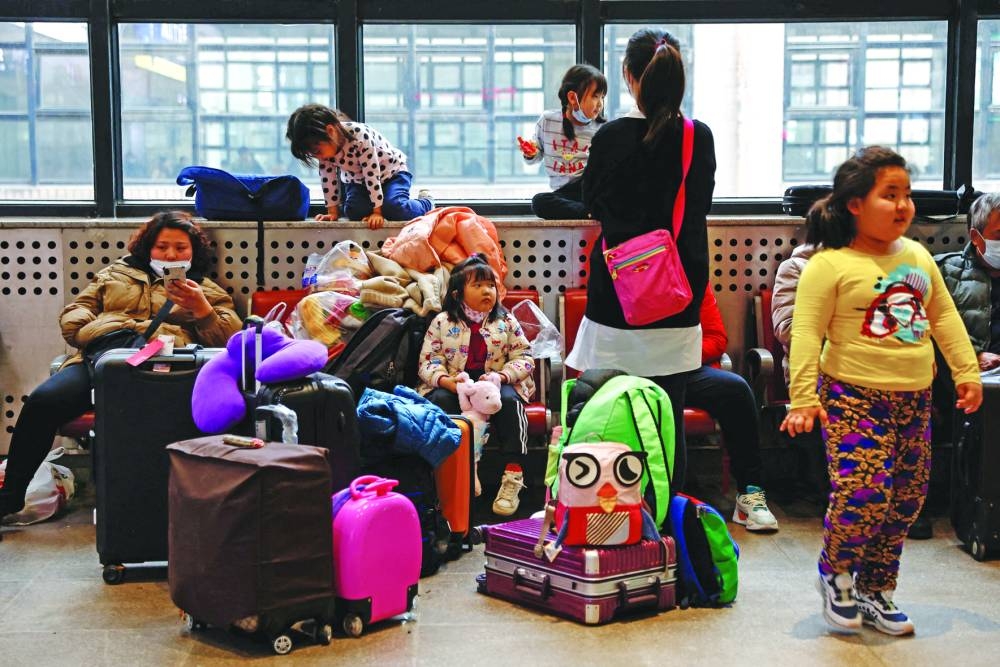 People wait to board a train at a railway station in Beijing.