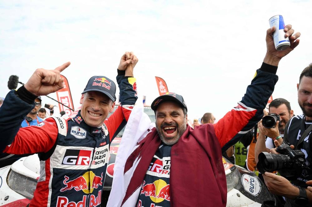 Toyota's driver Nasser Al-Attiyah (R) of Qatar and his co-driver Mathieu Baumel of France celebrate their victory after winning the Dakar Rally 2023, at the end of the last stage between between Al-Hofuf and Dammam, Saudi Arabia, on January 15, 2023. (Photo by AFP)