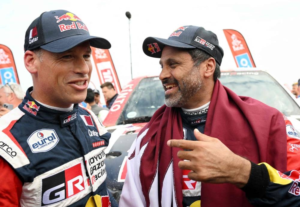 Toyota's driver Nasser Al-Attiyah (R) of Qatar and his co-driver Mathieu Baumel of France celebrate their victory after winning the Dakar Rally 2023, at the end of the last stage between between Al-Hofuf and Dammam, Saudi Arabia, on January 15, 2023. (Photo by AFP)