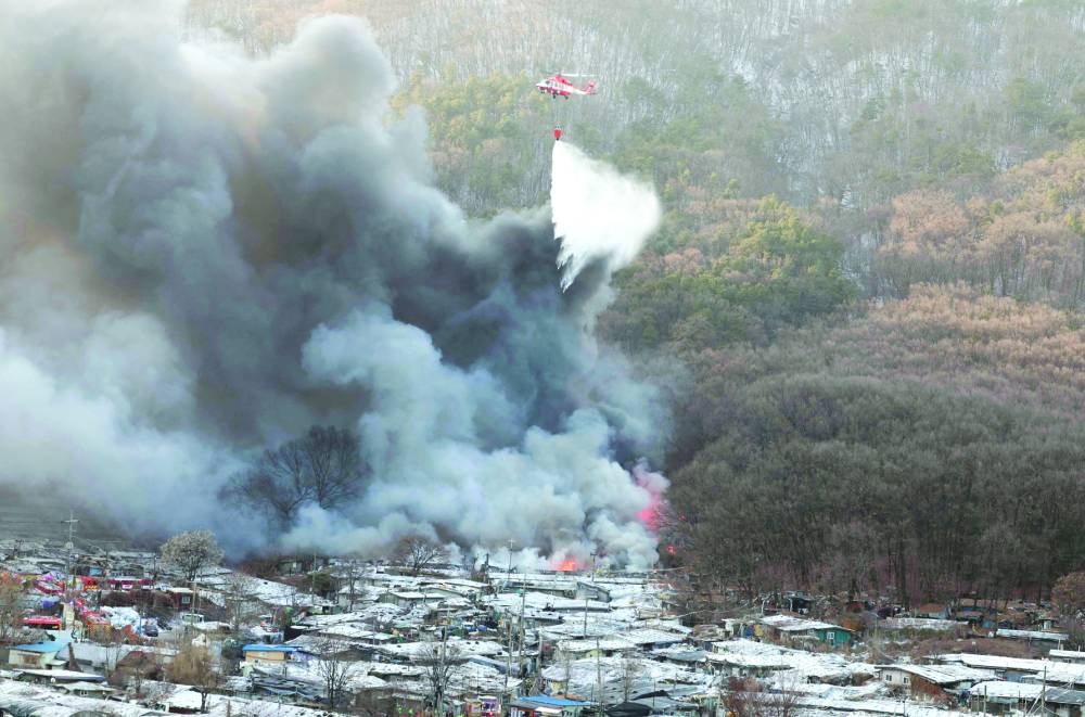 Firefighters try to extinguish a fire at the Guryong village, one of South Korea’s last remaining slums, in southern Seoul yesterday.