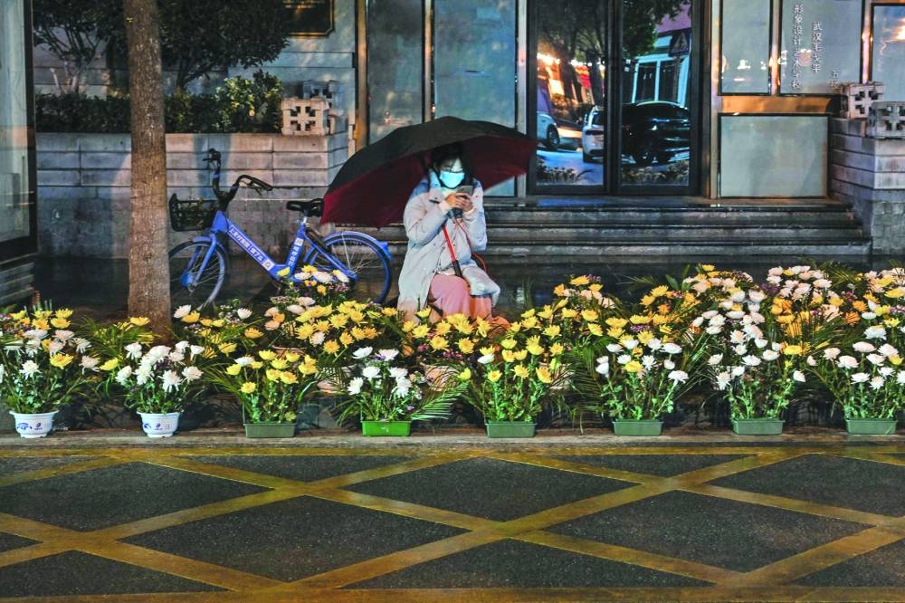 A woman selling flowers along a street waits for customers on the eve of the Lunar New Year in Wuhan, in China's central Hubei province.