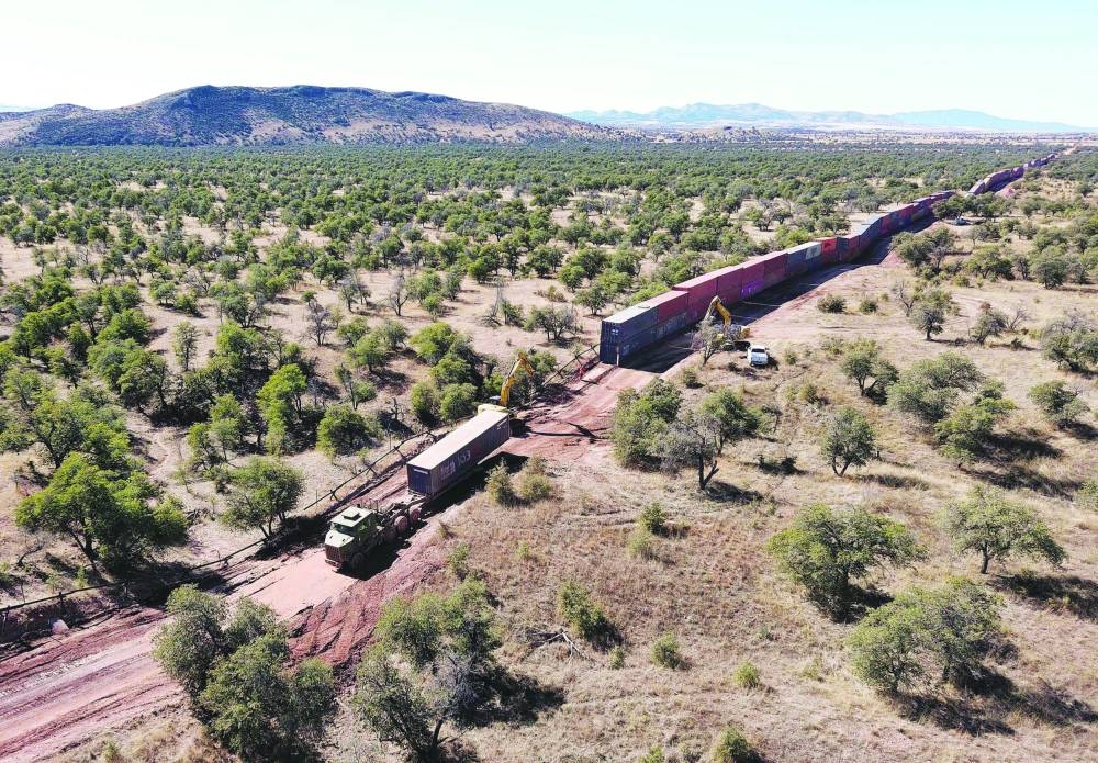 A truck drives away with a shipping container removed from a long row of those stacked to create a wall between the US and Mexico in the Coronado National Forest, near Hereford, Arizona.