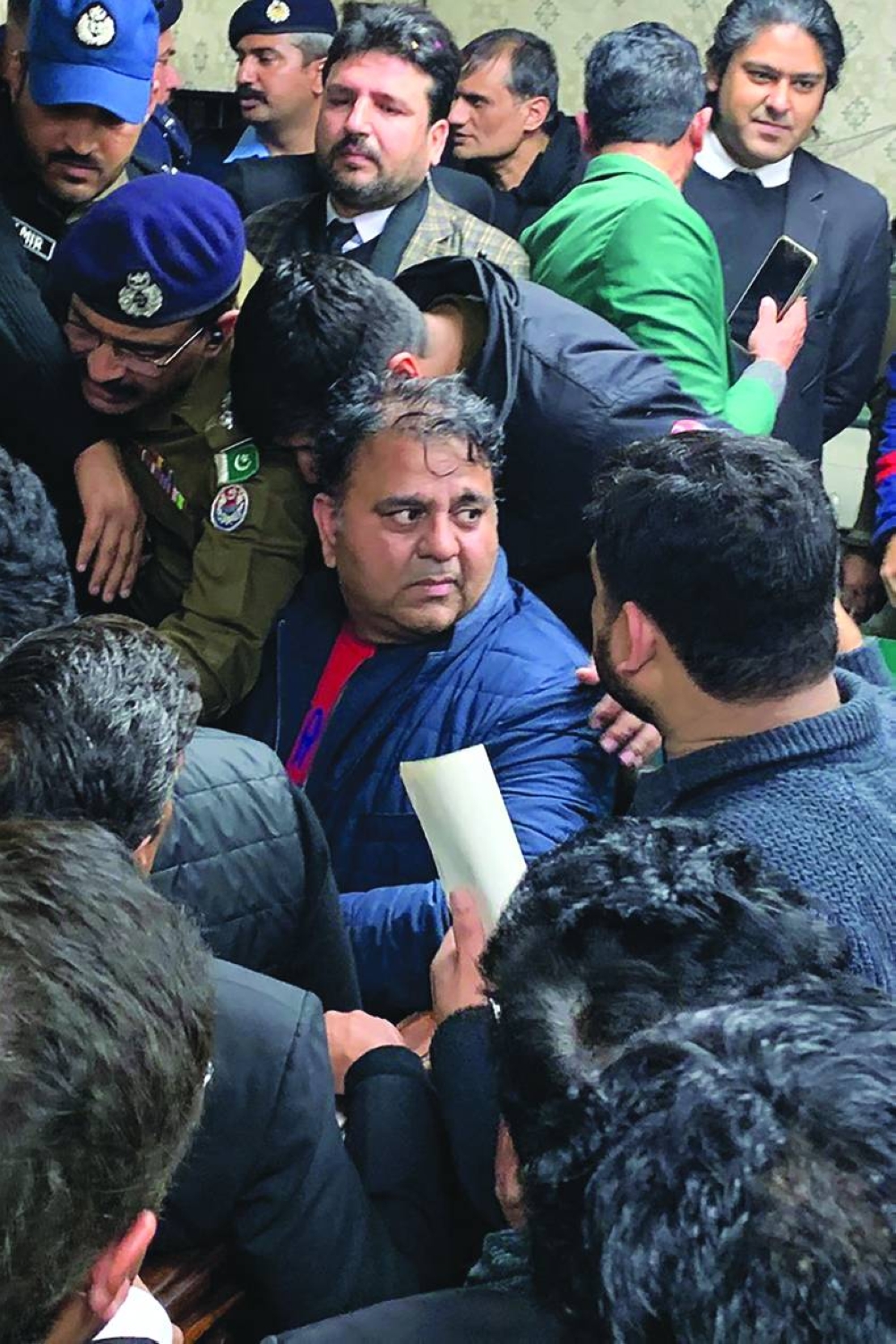 Police officials escort Fawad Chaudhry (centre) to present him before a court in Lahore yesterday. (AFP)