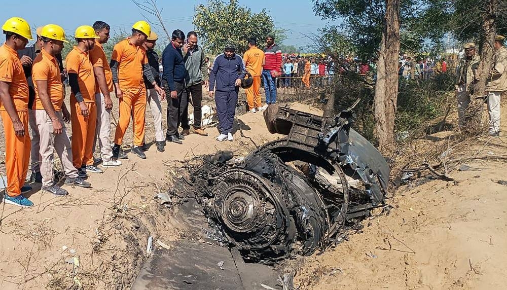 This handout photograph taken on January 28, 2023 and released by Rajasthan State Disaster Response Force (SDRF) shows local rescue authorities and military officials inspecting wreckage of a crashed aircraft. (AFP Photo / Rajasthan State Disaster Response Force)