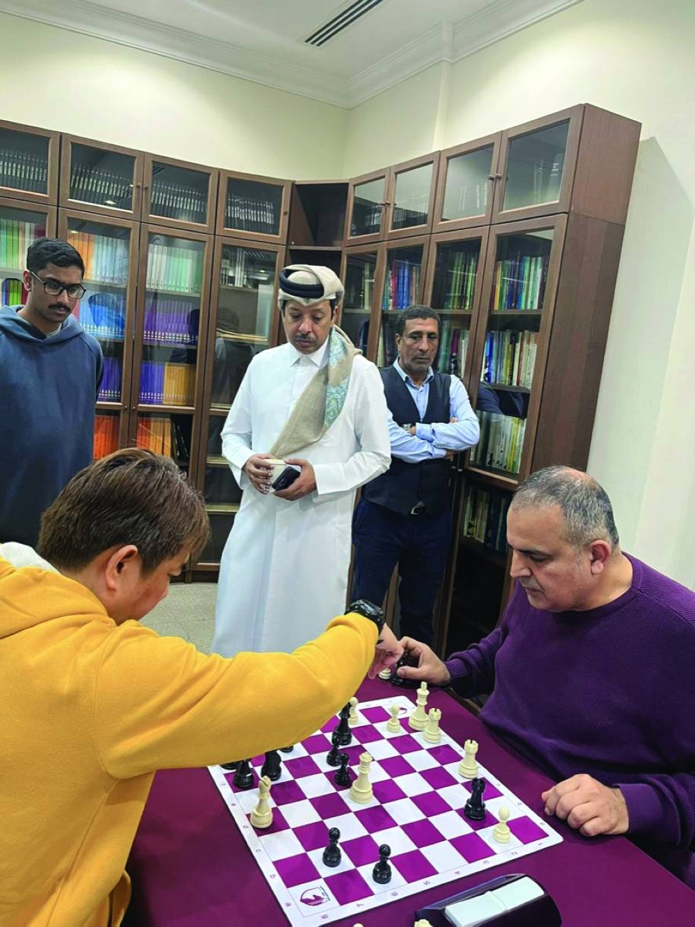 Players ponder a move as QCA president Mohamed al-Mudahka looks on.