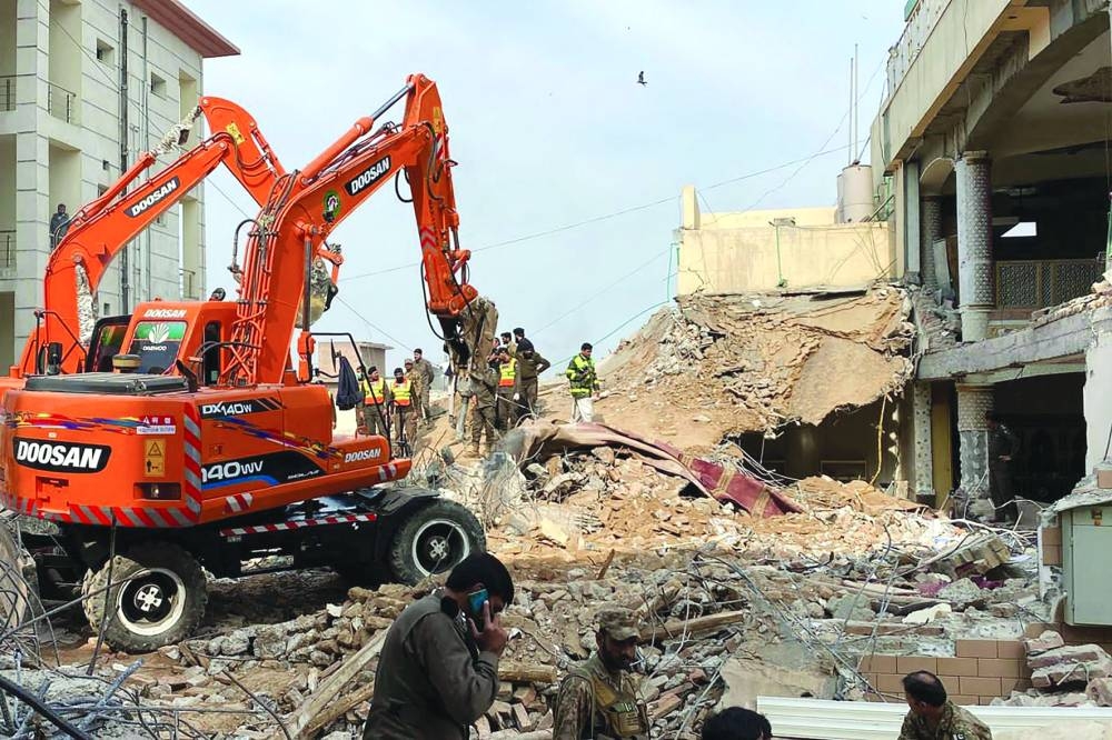 Authorities use heavy machinery yesterday to clear the rubble and search for victims a day after the suicide blast in Peshawar. (AFP)