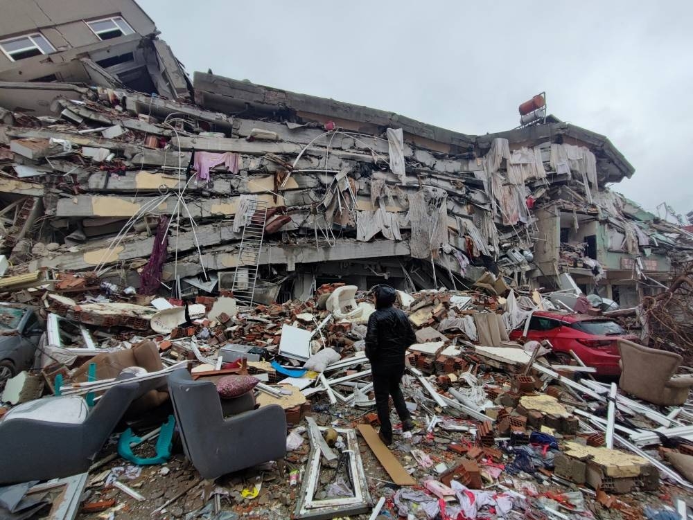 A man stands in front of collapsed buildings following an earthquake in Kahramanmaras, Turkey.  Ihlas News Agency (IHA) via REUTERS