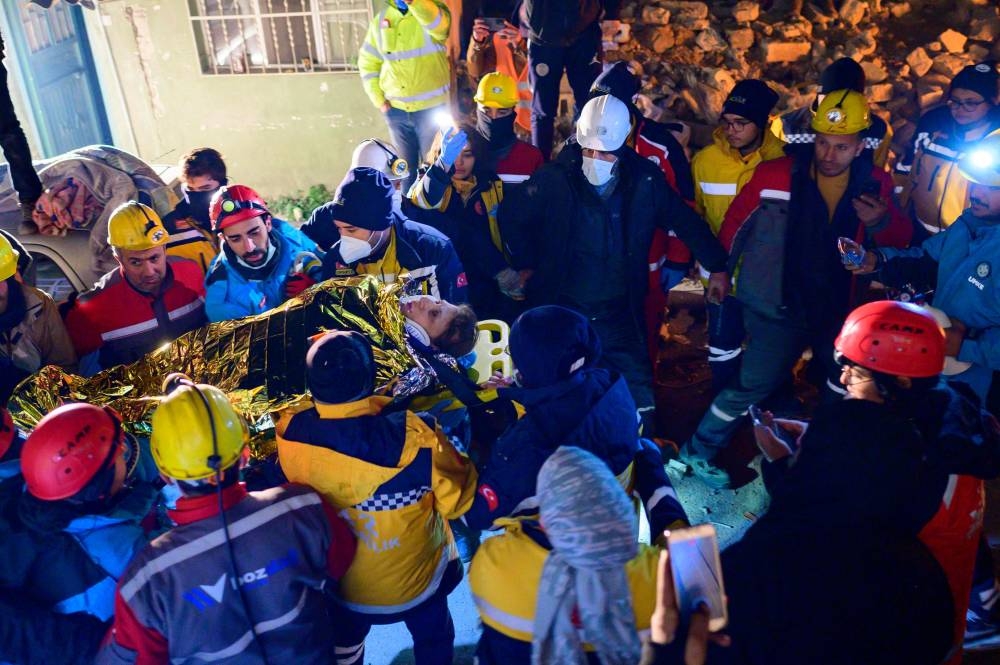 A Syrian woman is rescued from the rubble of a destroyed building in Hatay (AFP)