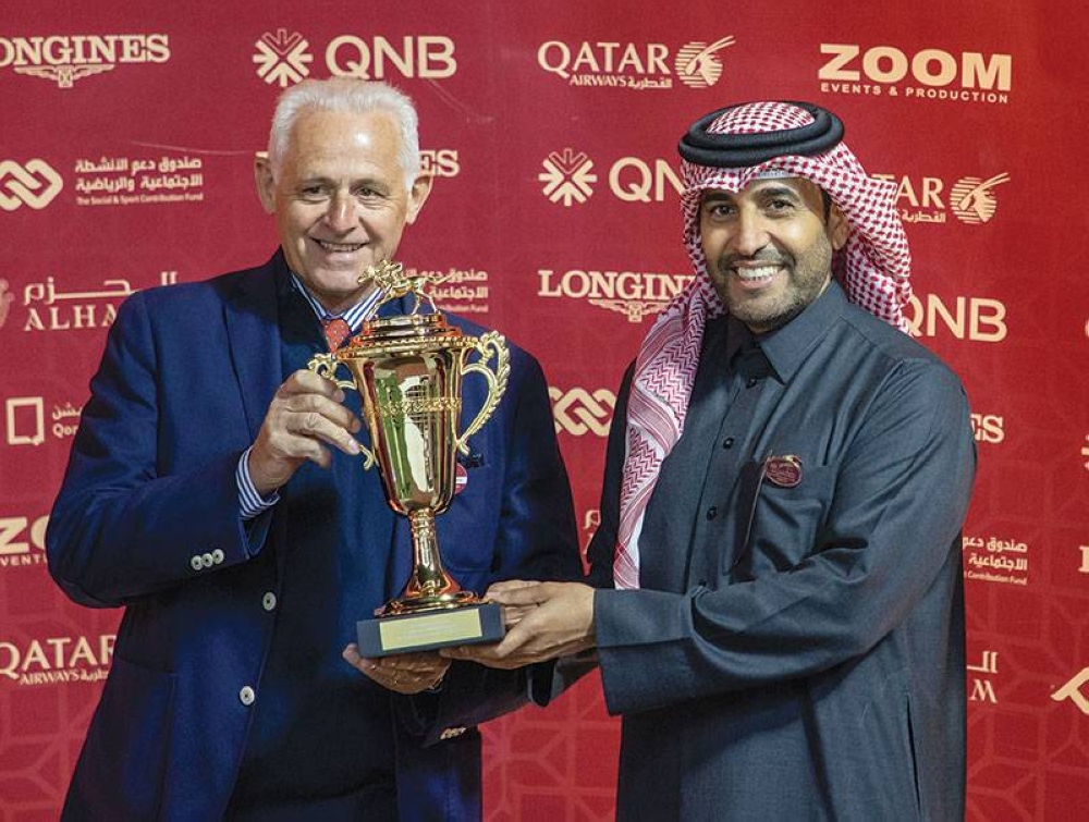 QREC chairman Issa bin Mohamed al-Mohannadi presents a trophy to trainer Alban de Mieulle after Equinoxe won the Al Rayyan Breeders Cup yesterday.