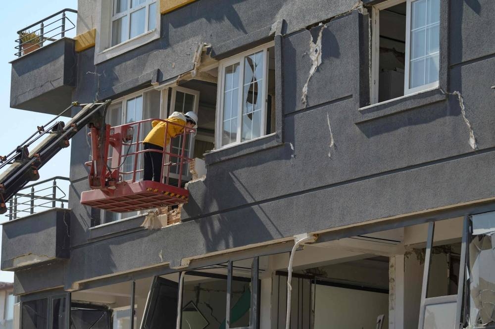 A woman stands on an aerial bucket as she is calling her two cats while a rescue team from the local NGO Haytap, helped by German and Austrian volunteers, try to find them in her destroyed building in Antakya, south of Turkey, where many animals are trapped in the rubbles after the February 6th earthquake, on February 18. AFP
