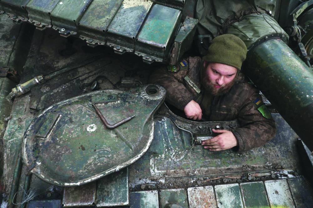 A Ukrainian serviceman (above) sits on his tank near a front line in the Kharkiv region amid the Russian invasion of Ukraine.