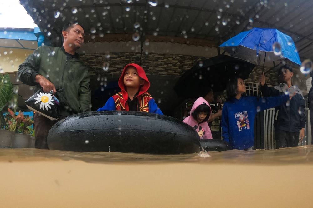 A family prepares to be evacuated from their home in a flooded area in Yong Peng, Malaysia's Johor state on March 4, 2023. (Photo by Mohd RASFAN / AFP)
