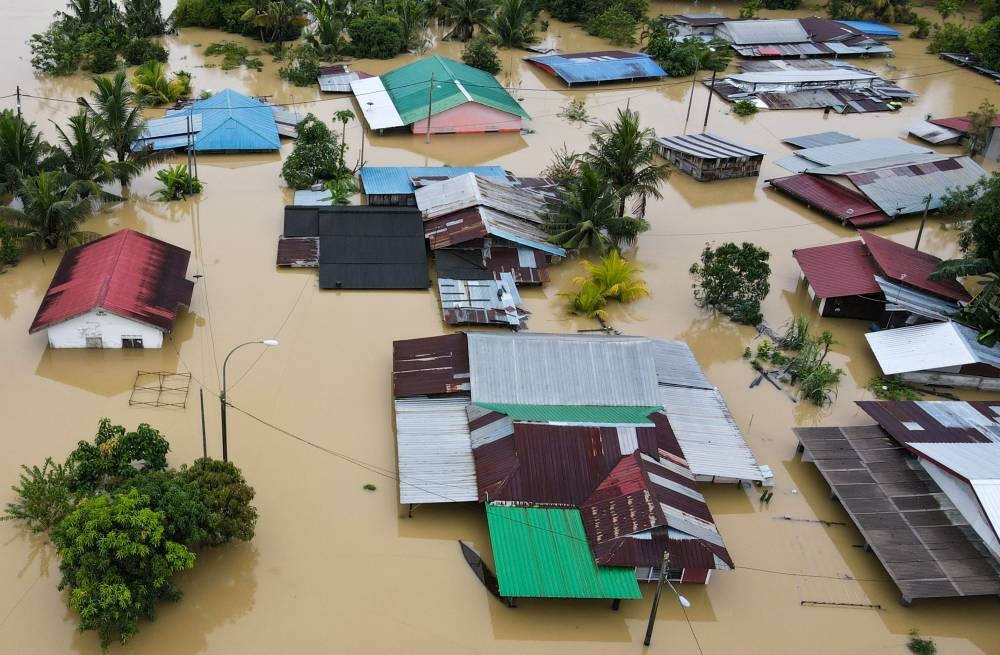 An aerial view shows flooded houses in Yong Peng, Malaysia's Johor state, on March 4, 2023. - At least four people have died and nearly 41,000 evacuated in Malaysia after floodwaters caused by "unusual" torrential rains lasting days swept through several states, officials said March 4. (Photo by Mohd RASFAN / AFP)