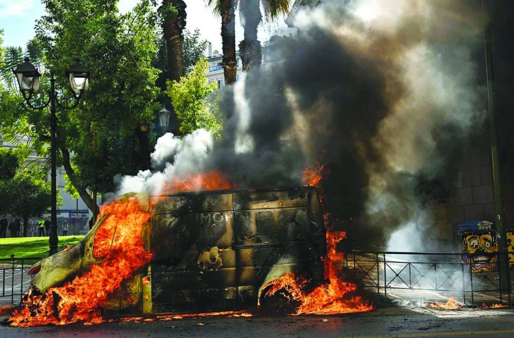 A van burns as clashes broke out in Athens yesterday during a nationwide day of mass strikes and protests over the country’s worst rail tragedy that killed 57 people last week. (AFP)