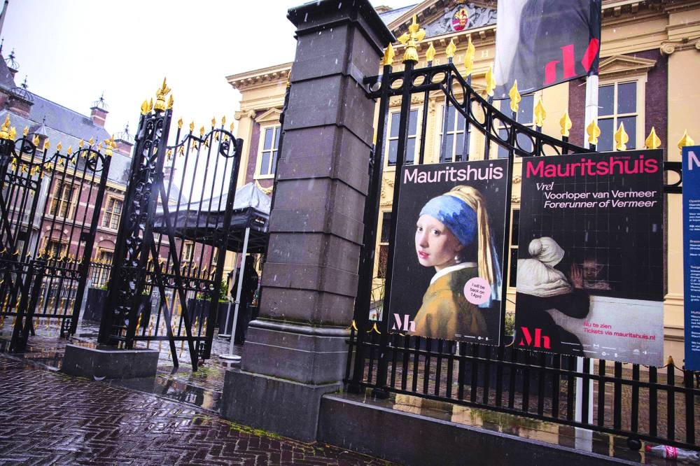 A visitor takes a picture with his mobile phone of an image designed with artificial intelligence, inspired by Girl with a Pearl Earring. (AFP)