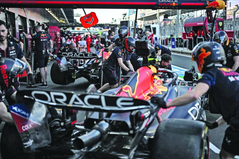 Mechanics wheel the car of Red Bull Racing’s Mexican driver Sergio Perez’ (front) and that of his Dutch teammate Max Verstappen (centre) after the first practice session at the Jeddah Corniche Circuit ahead of the 2023 Saudi Arabia Grand Prix. (AFP)