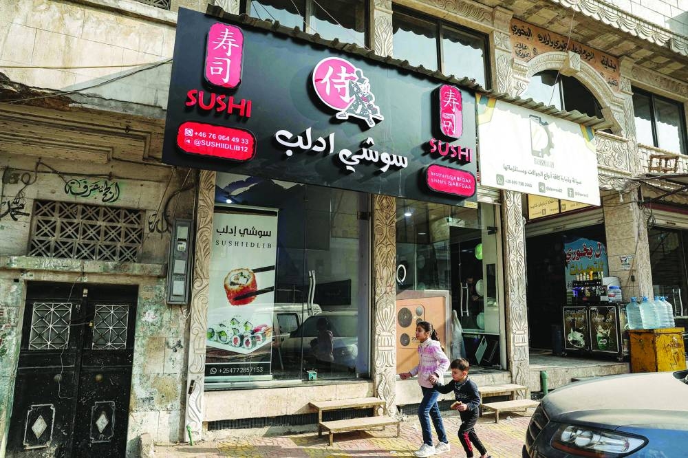 In this picture taken on January 29, children walk past the entrance of Islam Shakhbanov's sushi restaurant in Idlib.