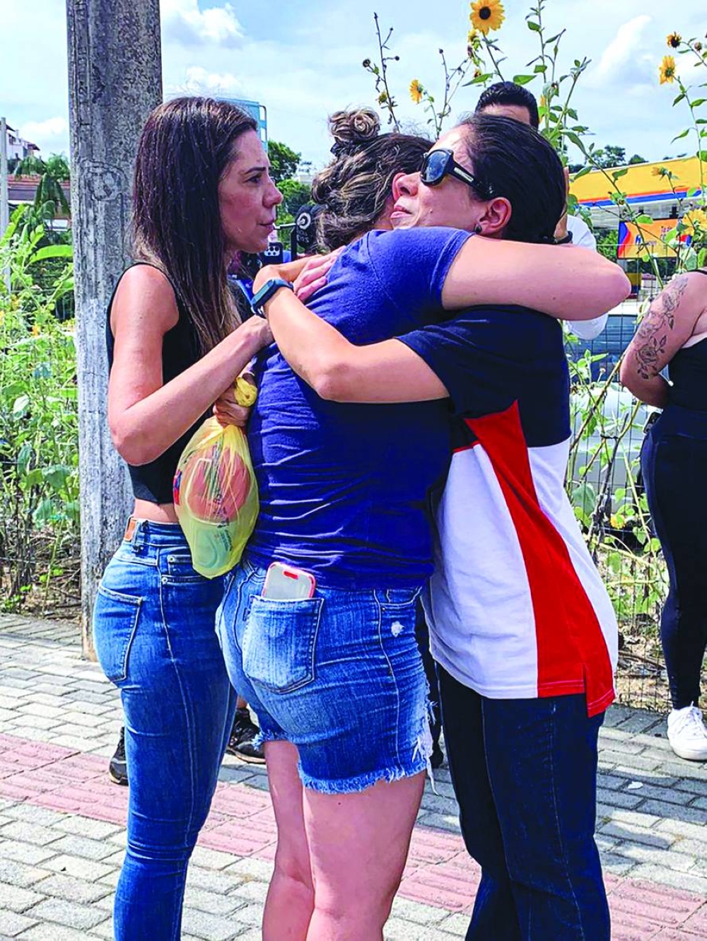 Women hug outside a pre-school after the attack in Blumenau in southern Brazilian state of Santa Catarina yesterday. (Reuters)