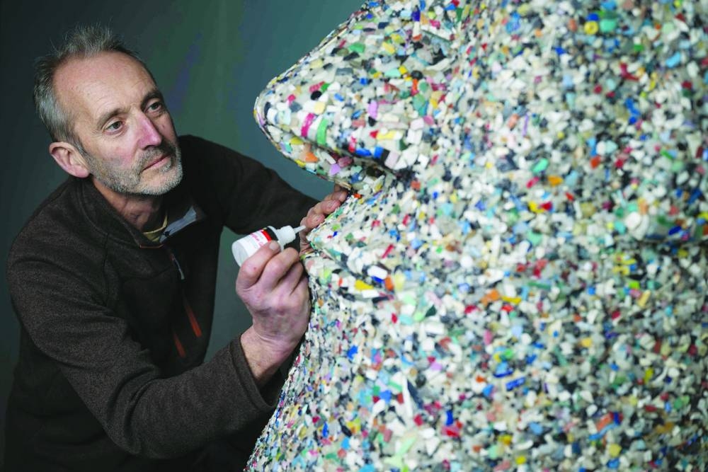 Artist and environmental activist Rob Arnold works on a sculpture called A Lesson of History that he created in 2017, inspired by the Moai heads on the Easter Island, entirely made from nurdles and other micro-plastics collected on the beach.