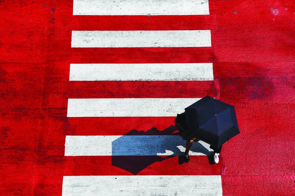 People hold an umbrella while crossing the street as temperatures hit a record high in Bangkok.