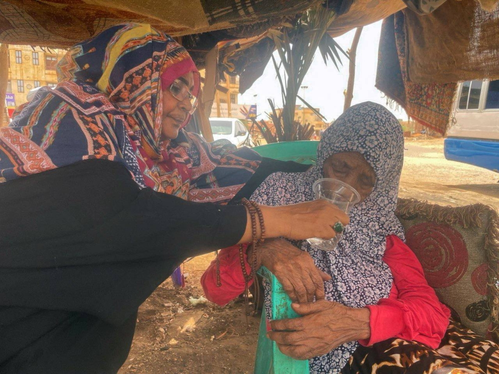 A woman is helped to drink water as she flees clashes between the paramilitary Rapid Support Forces and the army in Khartoum, Sudan. REUTERS