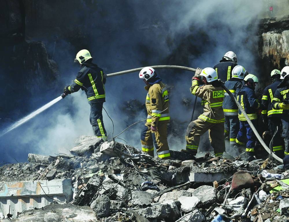 Rescuers work with an active water hose on the rubble of a damaged residential building in Uman, central Ukraine. (AFP)