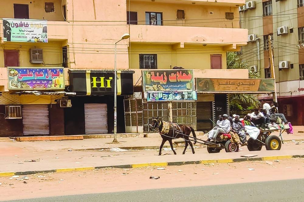 People travel on a horse-drawn wagon along a street as fighting continues in Khartoum.